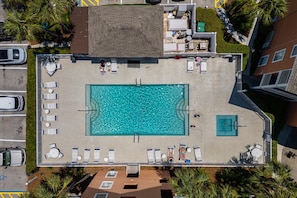 An aerial view of a rooftop swimming pool with lounge chairs, a small deck area, and surrounding greenery. - Gulf View 216 (Miramar Beach)