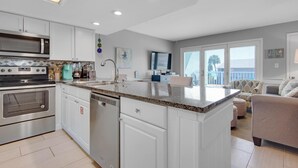 A modern kitchen with white cabinets, a stainless steel stove, and a granite countertop. - Gulf View 216 (Miramar Beach)