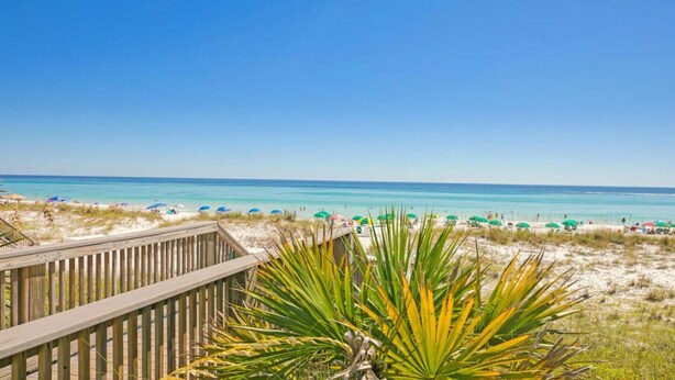 A beach with a wooden boardwalk and beach umbrellas. - Gulf View 216 (Miramar Beach)