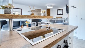 Une cuisine moderne dotée d’un plan de travail en bois, d’appareils électroménagers intégrés et d’un pare-feu en verre.