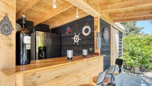 A wooden bar area with a refrigerator, a bottle of wine, and decorative items like a ship's wheel and a welcome sign. - Apartment 'Carpe Diem' with Shared Pool, Wi-Fi and Air Conditioning (Alicante (Alacant))