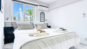 A bedroom with a bed, a nightstand, a window with a view, an air conditioning unit, and a wall-mounted thermostat. - Apartment 'Carpe Diem' with Shared Pool, Wi-Fi and Air Conditioning (Alicante (Alacant))