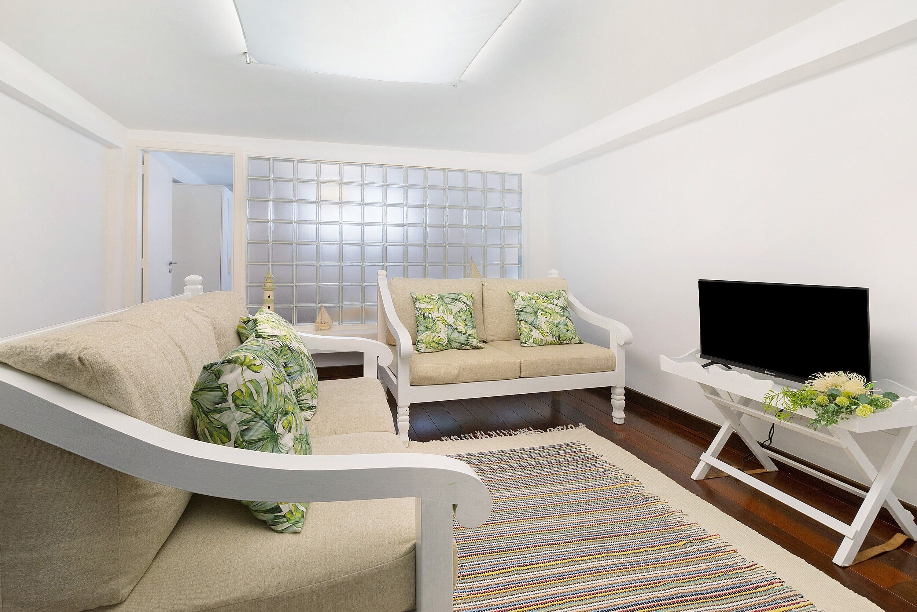 A modern living room with a sofa, a television, and a decorative plant.