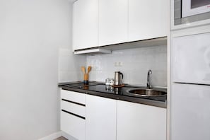 A modern kitchen with white cabinets, a stainless steel sink, and a built-in range hood.
