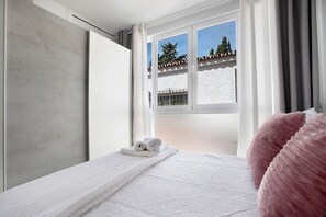 Une chambre à coucher avec un lit, une fenêtre avec des rideaux et une vue sur l’extérieur.