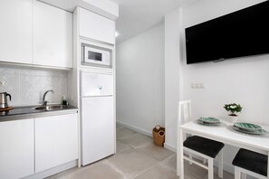 Une cuisine moderne avec des meubles blancs, un four à micro-ondes encastré et un réfrigérateur.