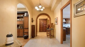 A hallway with a wooden cabinet, a dining table, and a chandelier.
