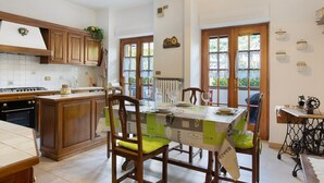 A kitchen with wooden cabinets, a dining table with chairs, a radiator, and a sewing machine.