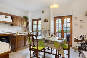 Une cuisine avec des meubles de rangement en bois, une table à manger avec des chaises, un radiateur et une machine à coudre.