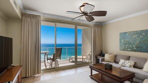 Une pièce avec un balcon, un ventilateur de plafond, un canapé, une table basse et un tableau.