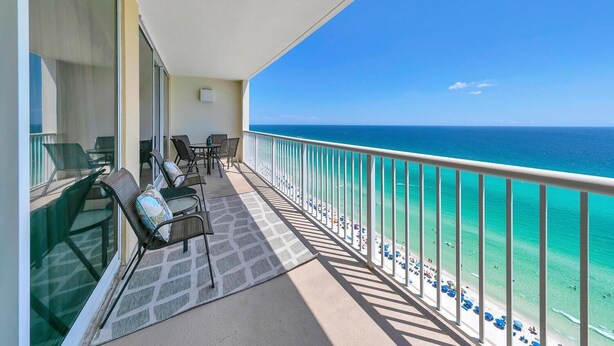 A balcony with a view of the ocean, furnished with chairs and a table.