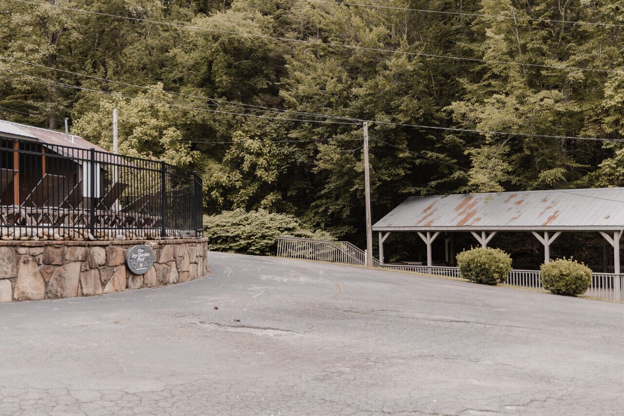 A building with a stone wall and metal fence, surrounded by trees.