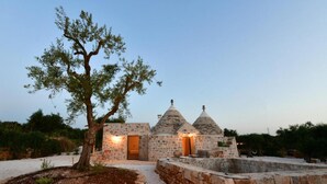 A stone building with a tree in front, a pathway, and a small structure with a dome roof.