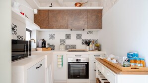 A modern kitchen with white cabinets, a Bosch oven, a microwave, and a wooden countertop.