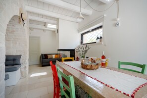 A dining area with a table set for two, a sofa, and a window with a view.