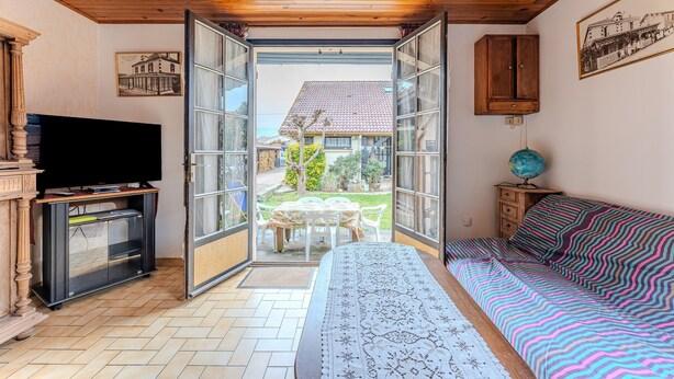 A room with a bed, a television, a cabinet, and a table with chairs. - Holiday Home 'Blanche Neige Mimizan' with Private Terrace and Shared Garden (Mimizan)
