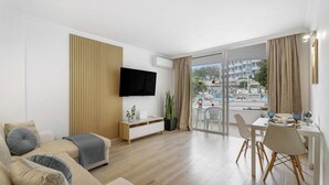 A modern living room with a sofa, TV, and dining area with a view.