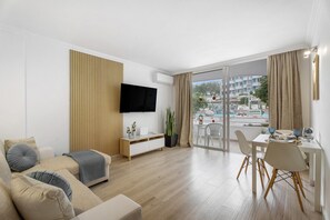 Un salon moderne avec un canapé, un téléviseur et un coin repas offrant une vue agréable.