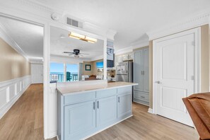 A kitchen with a large island, white cabinetry, and a view to the outside. - The Summit 1323 (Panama City Beach)