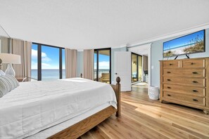 Een slaapkamer met een groot bed, een kaptafel en uitzicht op zee.