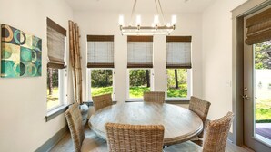 A dining area with a round table, wicker chairs, and a chandelier. - Shore Thing Getaway (Miramar Beach)
