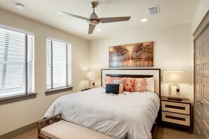 Quarto com uma cama, duas mesas de cabeceira, um ventilador de teto e um quadro na parede.