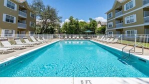A rectangular swimming pool with a 5 ft depth marking, surrounded by lounge chairs and a white fence. - Heron's Watch Way 4104- Coach's Sand Dollar (Santa Rosa Beach)