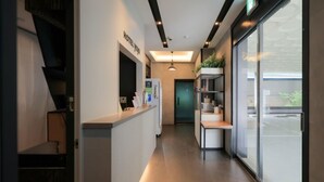Ein Hotel-Empfangsbereich mit modernem Design, einem Empfangstresen, einer Glastür zum Eingangsbereich und einer sichtbaren Treppe.