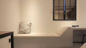 Ein schlichtes Zimmer mit integrierter Sitzbank, einem kleinen Tisch und einem Fenster.
