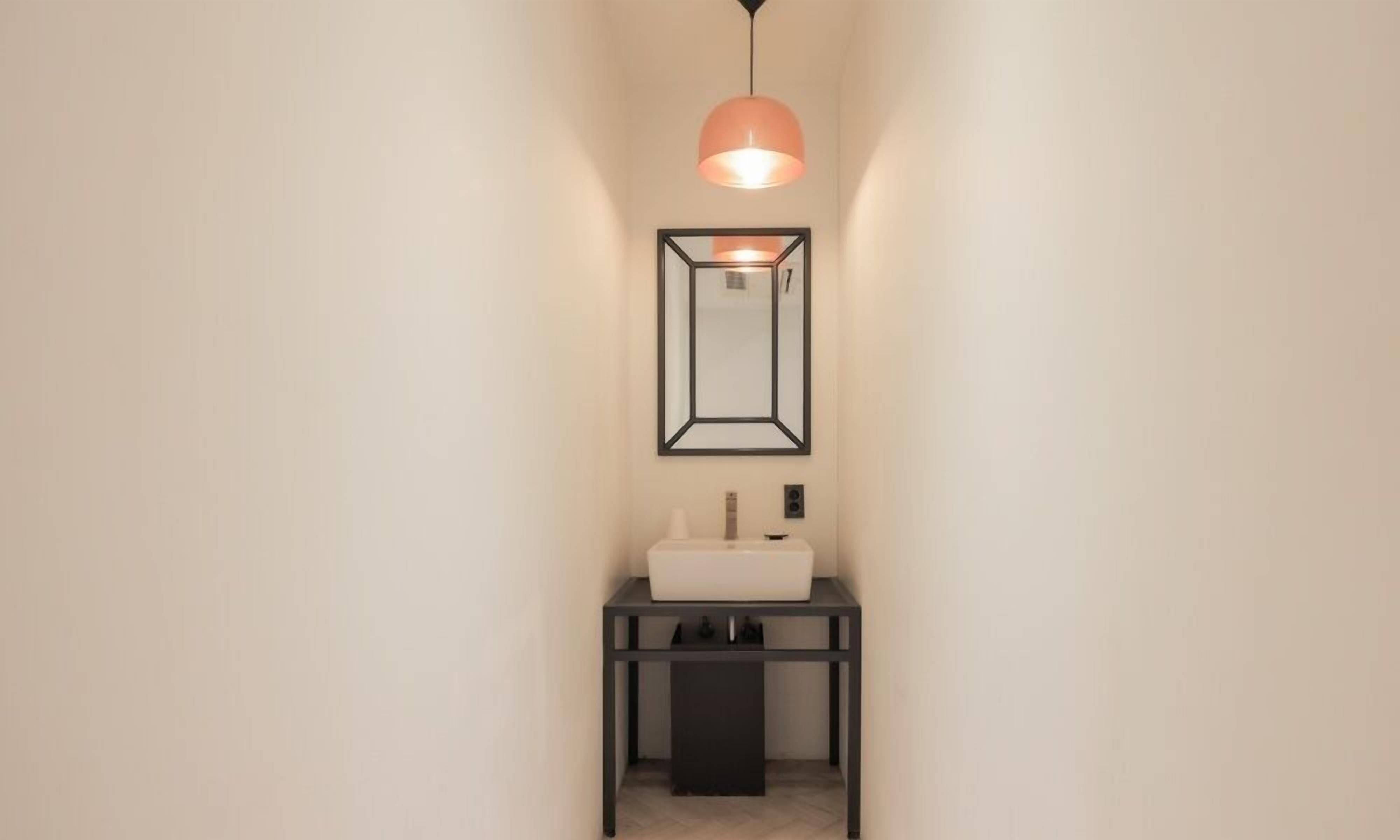 A modern bathroom with a white sink, a black vanity, and a pendant light.