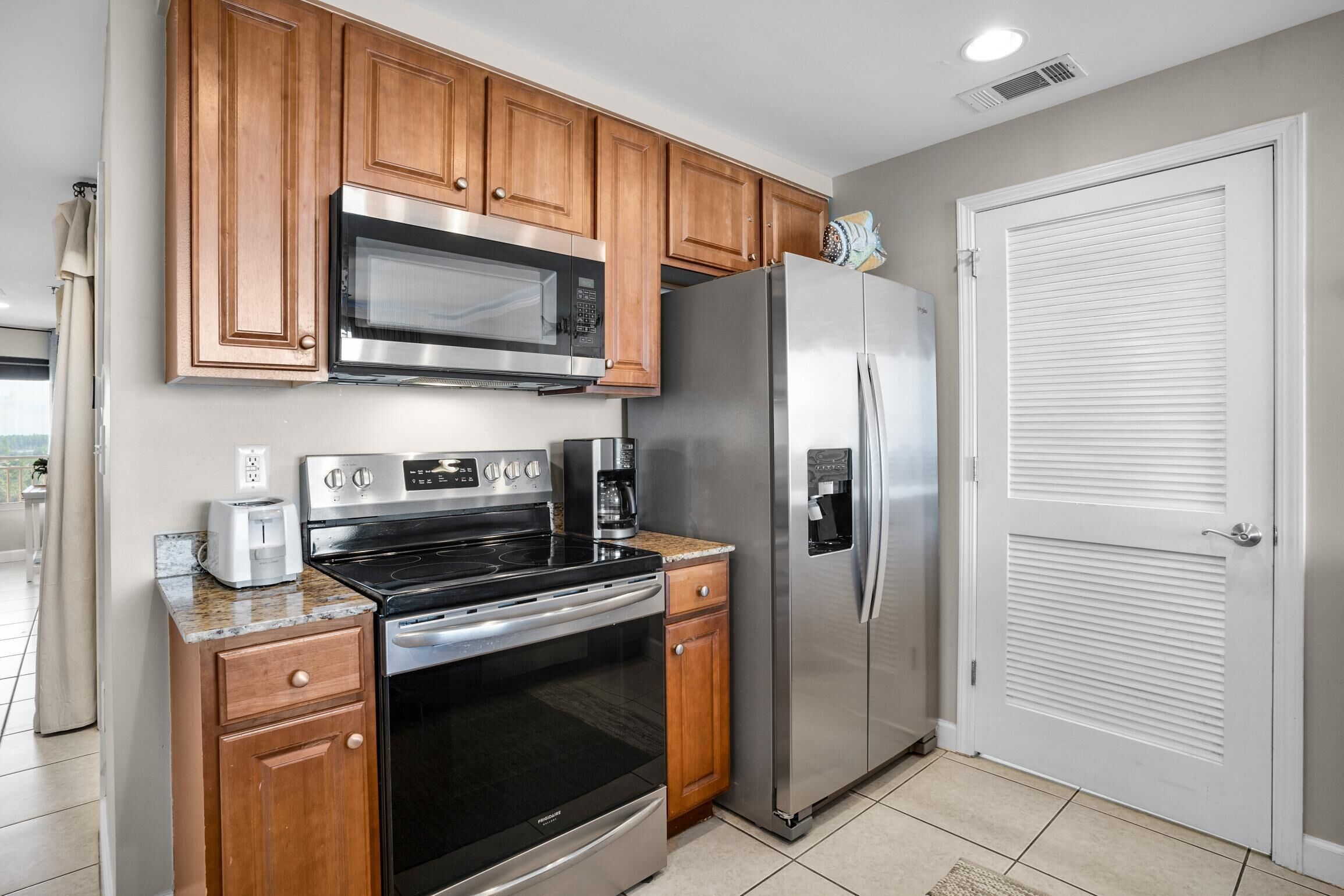 A kitchen with wooden cabinets, stainless steel appliances, and a white door.