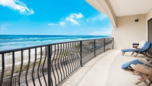 Un balcon avec vue sur l’océan, deux fauteuils et une rambarde.