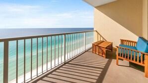 A balcony with a view of the ocean, a wooden table, and a blue chair. - Majestic Beach Towers 1-1911 (Panama City Beach)