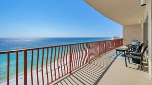 A balcony with a view of a beach and ocean, a red railing, and outdoor furniture. - Hidden Dunes 1802 (Panama City Beach)