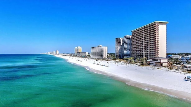 A beachfront hotel with multiple high-rise buildings, a sandy beach, and clear turquoise waters. - Hidden Dunes 1802 (Panama City Beach)