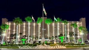 A hotel with multiple floors, palm trees, and flags. - The Summit 924 (Panama City Beach)