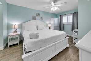 A bedroom with a bed, nightstands, a ceiling fan, and artwork on the wall. - The Summit 924 (Panama City Beach)