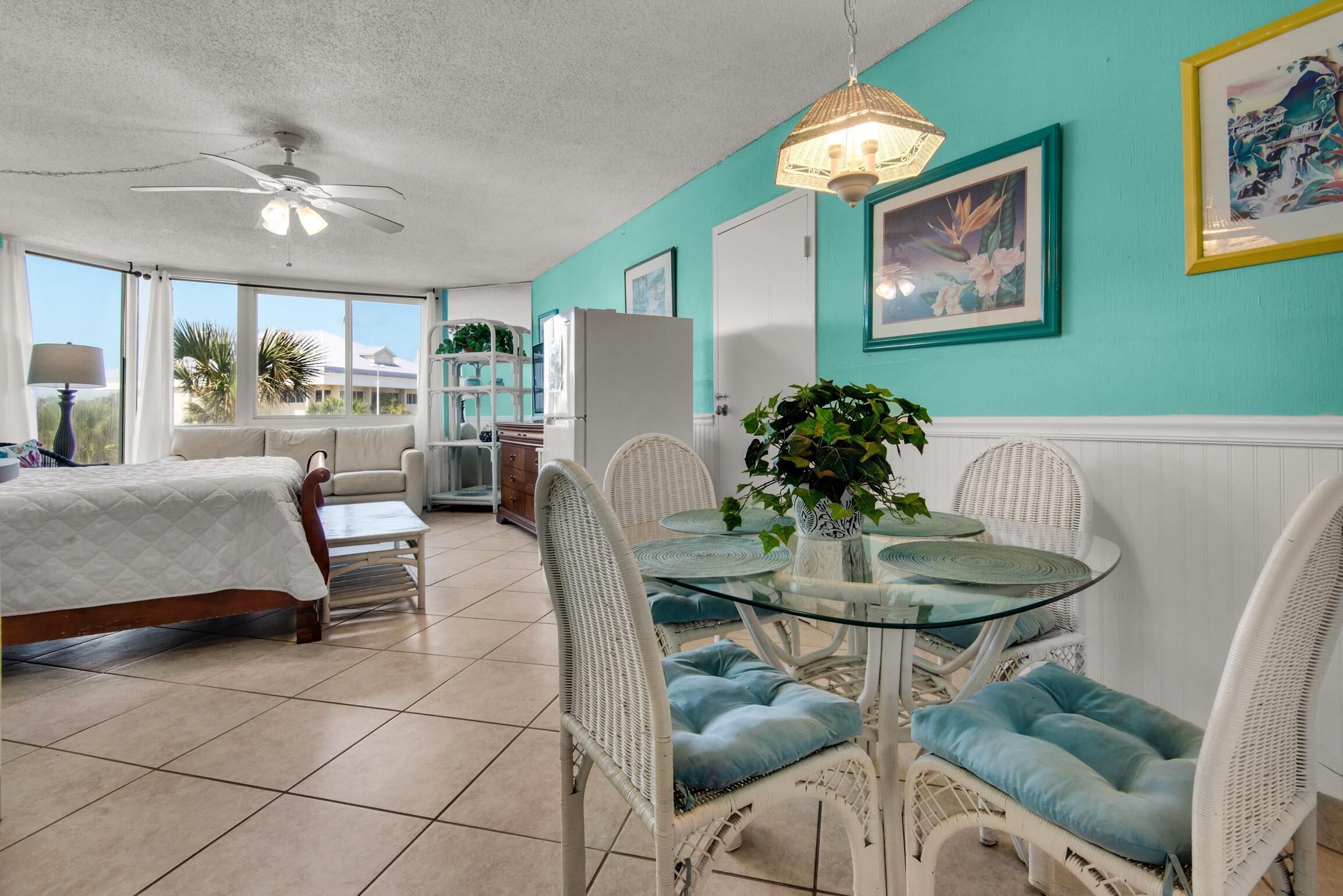 A bright, airy room with a bed, dining table, and chairs.