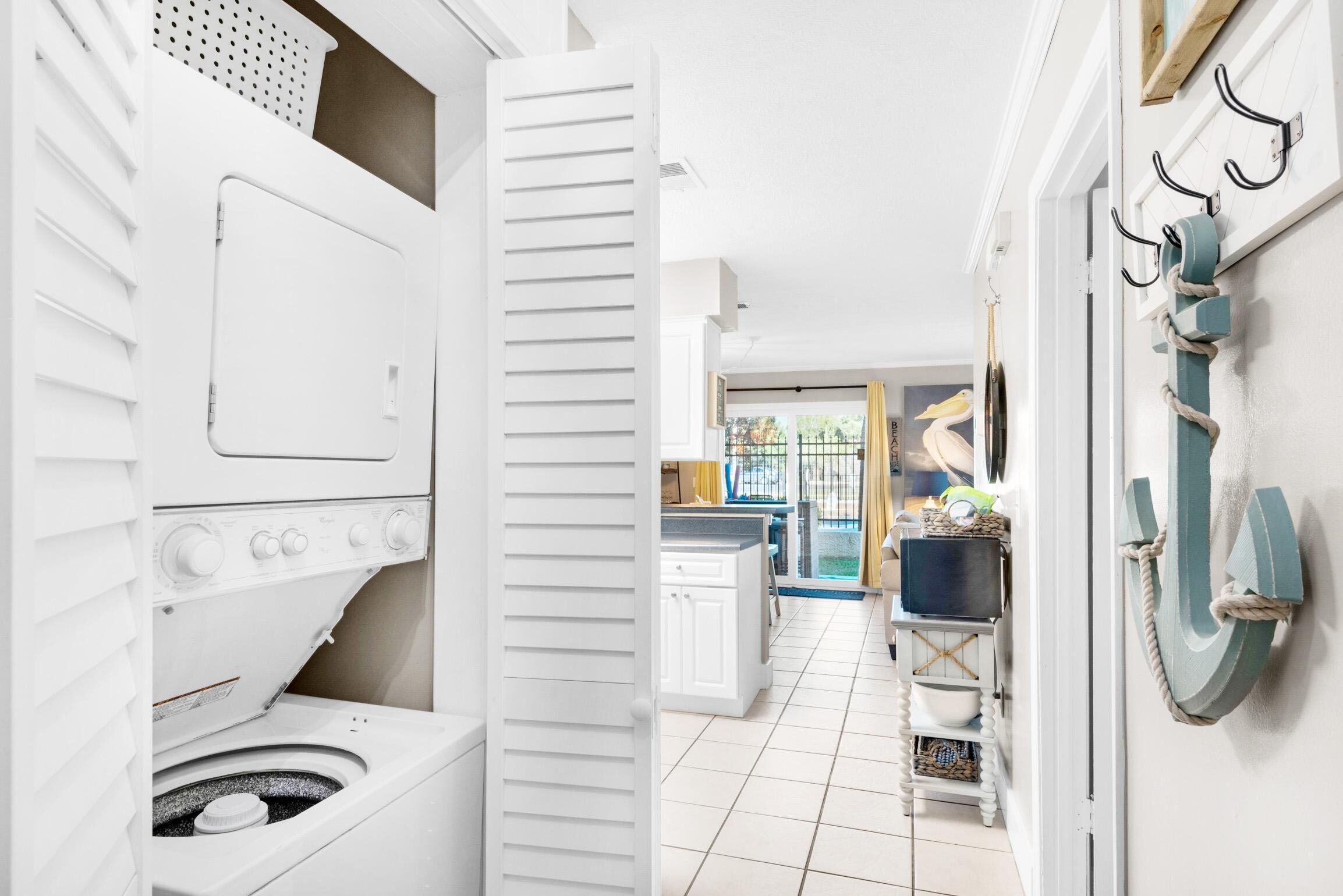A laundry room with a washing machine, dryer, and open closet door.