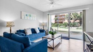 Ein modernes Wohnzimmer mit einem blauen Sofagarnitur, einem Couchtisch und einem Deckenventilator.