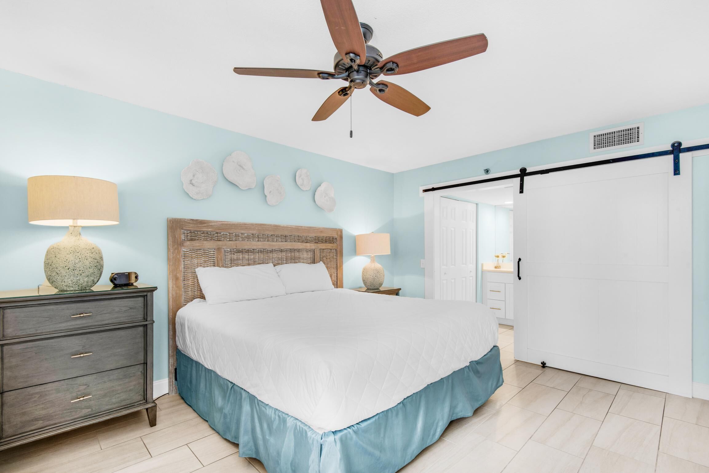 A bedroom with a bed, nightstands, a ceiling fan, and a wardrobe.