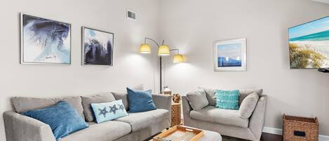 A living room with two grey sofas, a wooden coffee table, and a floor lamp.