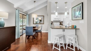 Une cuisine moderne avec des meubles blancs, un four à micro-ondes et un coin repas comprenant une table et des chaises.