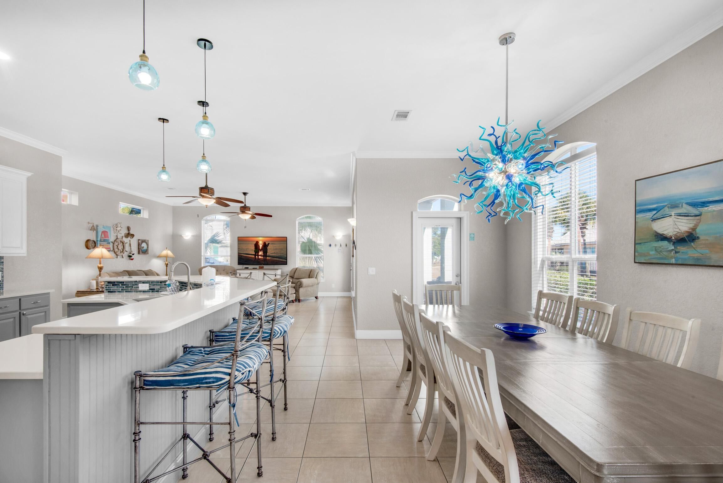 A modern kitchen with a central island, bar stools, and pendant lighting.