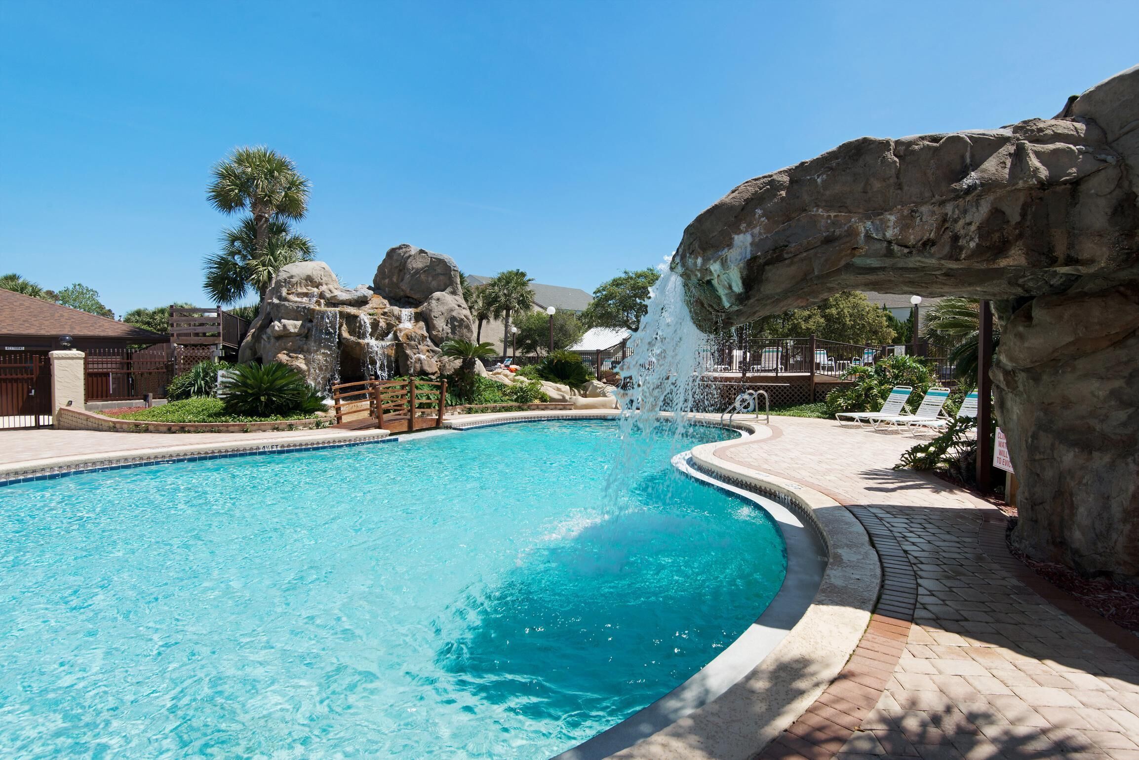 Una piscina con cascada, rodeada de formaciones rocosas y palmeras.