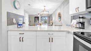 A modern kitchen with white cabinetry, a built-in microwave, and a coffee machine. - Portside R4 (Panama City Beach)