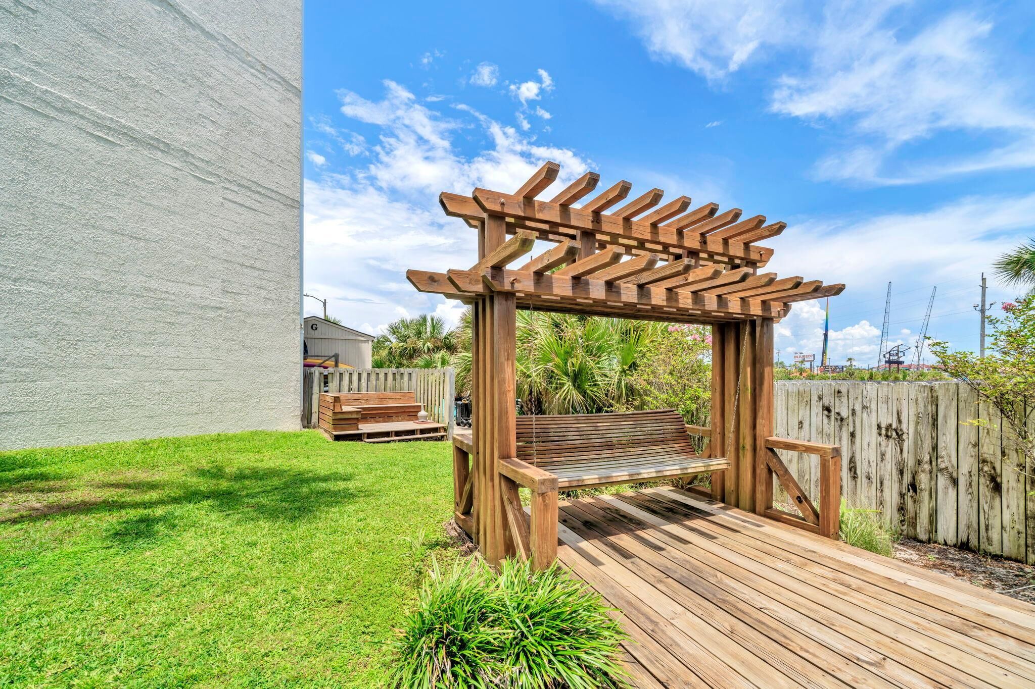 Une structure de pergola en bois dans un jardin, avec un banc en bois placé en dessous.