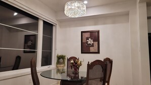 A dining area with a round glass table, two wooden chairs, a chandelier, and a framed picture on the wall. - Escape to our chic casita where modern comfort meets serene surroundings.  (Cambridge)