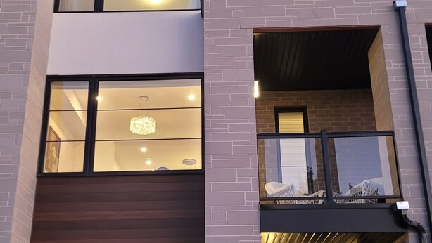 A modern two-story building with large windows, a garage, and a balcony. - Escape to our chic casita where modern comfort meets serene surroundings.  (Cambridge)
