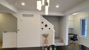 A modern kitchen with a black countertop, white cabinetry, and a staircase leading to another level. - Escape to our chic casita where modern comfort meets serene surroundings.  (Cambridge)
